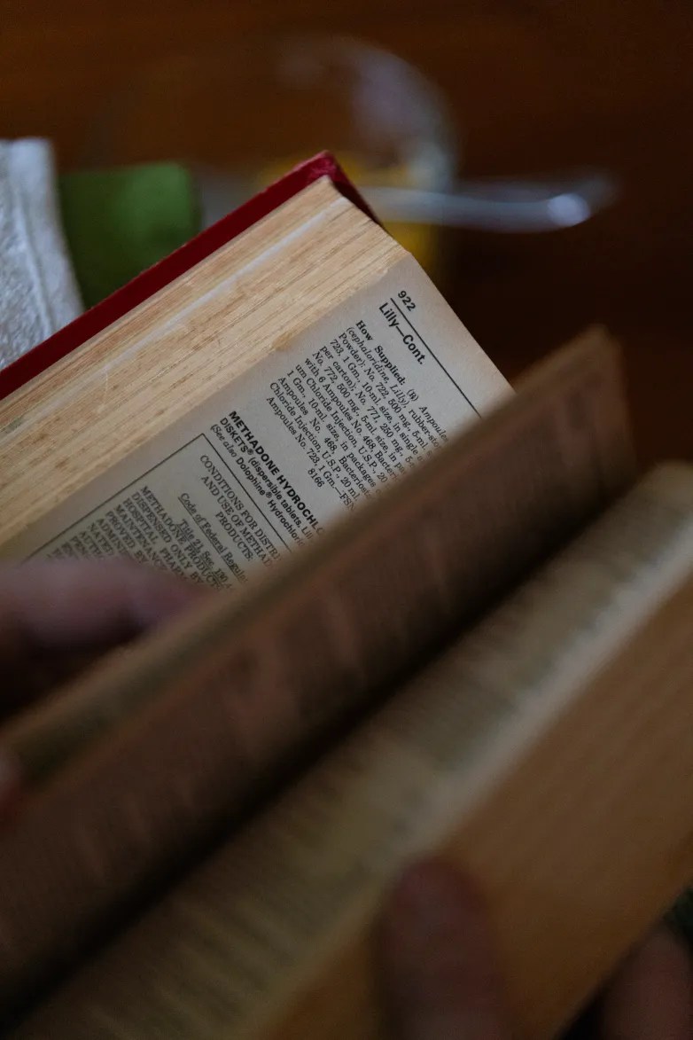 An open book shows a page with small printed text including "Methadone Hydrochloride."