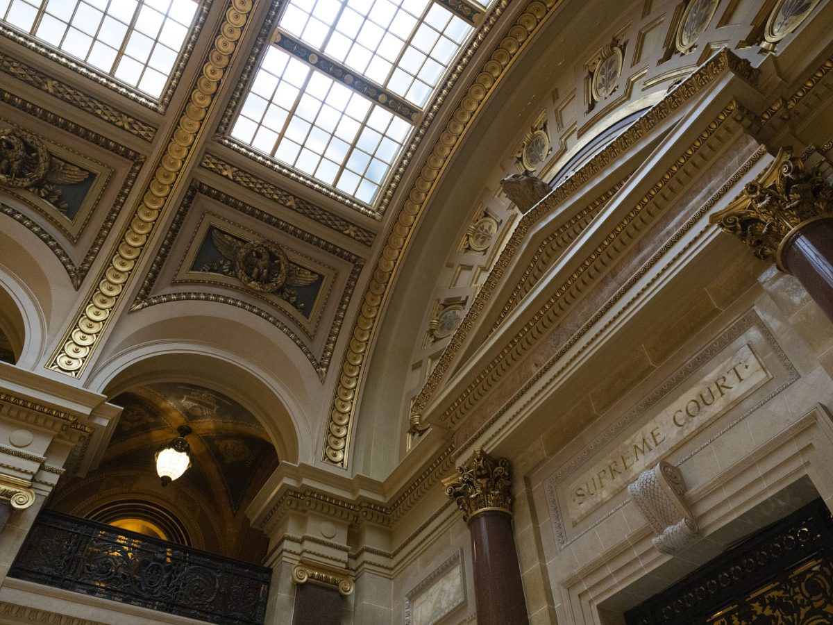 An ornate interior with tall columns, decorative arches and a glass ceiling, with "SUPREME COURT" carved above a doorway.